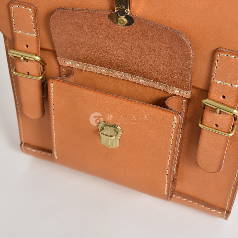 職人手作皮革經典學院風迷你後背包，淺棕色，展示正面細節，包含翻蓋、金屬釦、側面皮帶及車縫線。