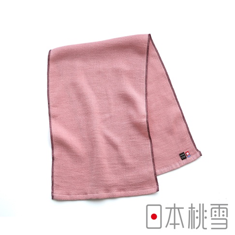這是一條日本桃雪品牌的今治輕量快乾運動長毛巾，呈現溫潤的乾燥玫瑰粉色，表面具有細緻的織紋質感，邊緣以深色縫線精緻收邊，毛巾右下角縫有品牌標籤與今治毛巾認證標章，整體風格簡約優雅，適合運動或日常使用。