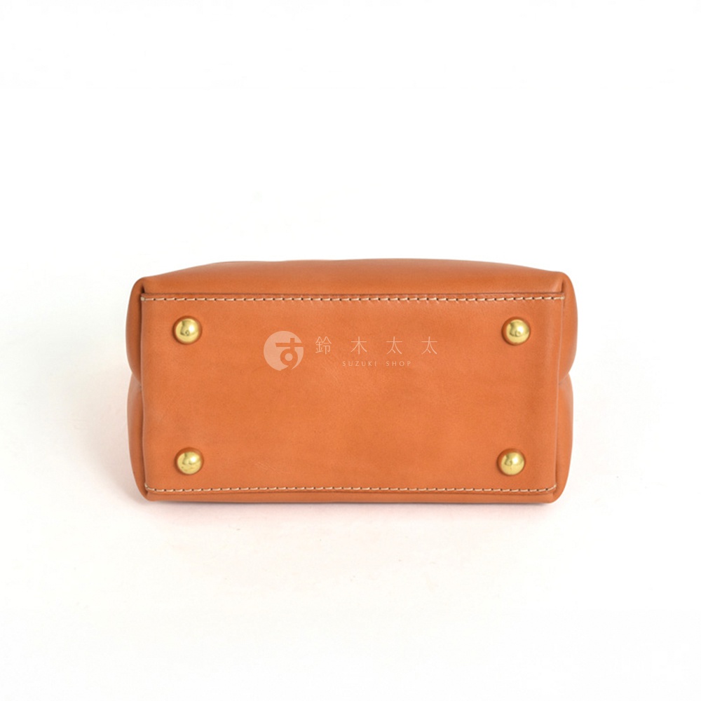 職人手作皮革迷你托特包 T-11，展示的是其中一款的底部，採用 tan 色皮革製成，配有四個黃銅色的腳釘，邊緣有細緻的白色縫線。