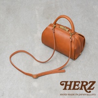 棕色皮革製成的職人手作 Organ 兩用口金手提包，附有可調節長度的斜背帶。包包設計簡潔，帶有復古的口金開合和提把，展現皮革的自然質感。