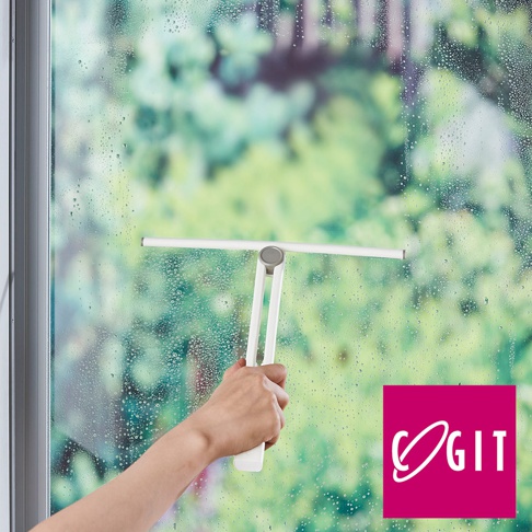 一支白色的360度磁吸旋轉刮水刷，由塑膠材質製成，手柄部分為白色，刮頭為白色，正用於清潔佈滿水珠的玻璃窗。