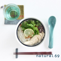 海軍風條紋丼碗，內盛有米線、雞肉片、檸檬片、香菜及辣椒。碗邊緣有藍色與白色條紋。旁邊擺放著一個藍綠色湯匙、一塊彩色布墊、一杯水以及一雙深紅色筷子。