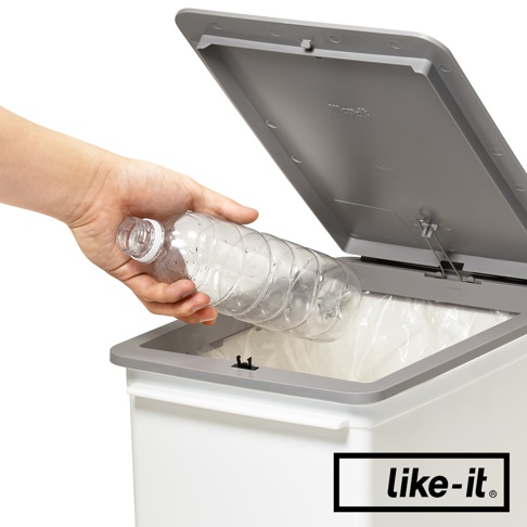 手持透明塑膠瓶，準備丟入白色掀蓋式垃圾桶。垃圾桶為高版設計，垃圾桶蓋為灰色，內部有垃圾袋。