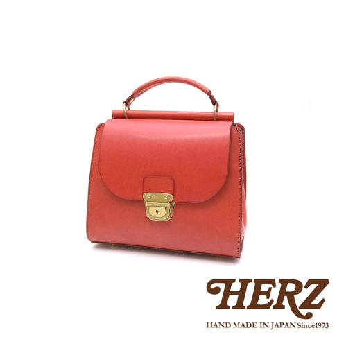 日本HERZ 職人手作紅褐色皮革瓦風兩用包，帶有金色鎖扣，旁邊印有品牌標誌。