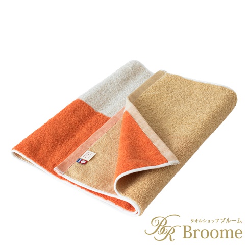 今治KAKUTERU純棉毛巾，採用玩轉色塊設計，包含橘色、米白及淺褐色。毛巾材質為純棉，觸感柔軟，表面呈現細膩的織紋。