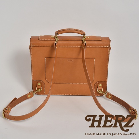 棕褐色皮革製作的傳統歐風三用學生包，帶有金屬扣環和可調節肩帶，正面有品牌壓印和方形插袋。