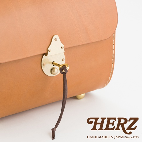 職人手作皮革復古杜勒斯手提包，採用光滑棕褐色皮革製成，配有黃銅鎖扣和鑰匙，鑰匙上繫有深棕色皮革繩。