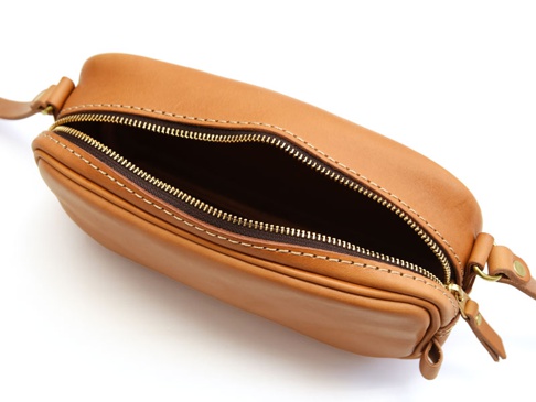 職人手作皮革隨身單肩小包，採用棕褐色皮革製成，設有黃銅色拉鍊，整體設計簡潔，強調皮革質感。