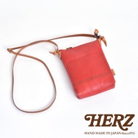 紅色職人手作皮革直式隨身單肩包，附有皮質長背帶。包包正面有一個方形外袋，邊緣有縫線裝飾。