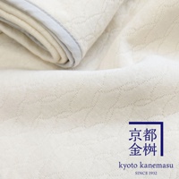 米白色天絲棉絎縫單人毯，織紋細緻，邊緣有淺灰滾邊。右下角有藍色框的日文及英文品牌標誌。