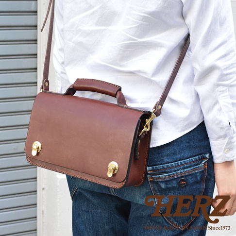 職人手作棕色皮革經典兩用迷你單肩包，配有頂部提把、可拆卸肩帶及兩個黃銅色鎖扣。