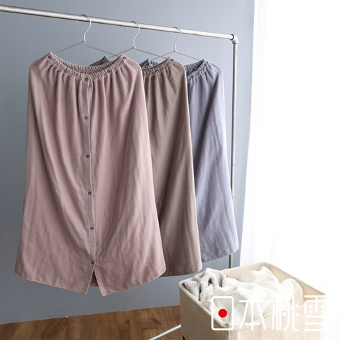 三件棉紗混紡平口鬆緊浴巾浴裙，分別為粉色、棕色和灰色，皆有鈕扣設計，掛於掛架上。