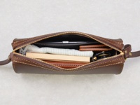 職人手作皮革Organ極簡風拉鍊單肩包，深棕色皮革，拉鍊開啟，內部可見手機、薄型錢包、鑰匙圈及條紋布料。