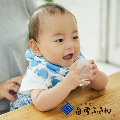 嬰兒配戴藍白友禪染圖案拭巾，拭巾上有白色的小兔子圖案，材質應為棉質。