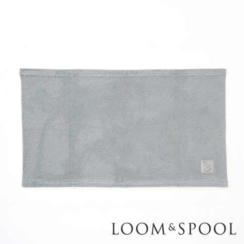 淺藍色純棉毛巾，帶有品牌標籤和LOOM&SPOOL的文字標誌