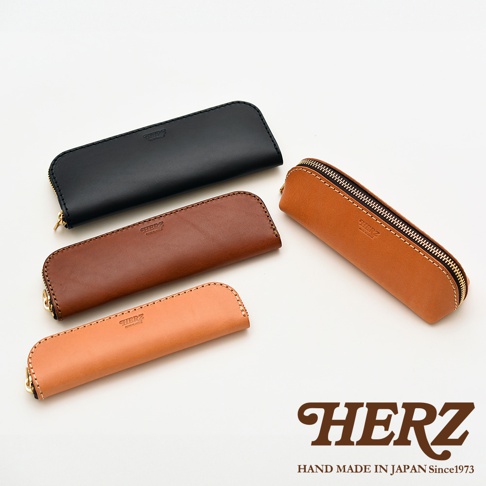 四個皮革筆袋，包含黑色、深棕色、淺棕色和駝色，皆帶有拉鍊和品牌標誌。