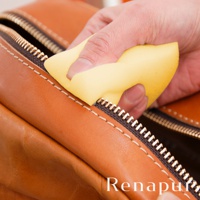 手持黃色海綿擦拭棕色皮革製品的拉鍊。