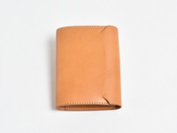 淺棕色皮革製成的A6記事本書套，簡約設計，邊緣有縫線裝飾，整體呈長方形，有翻蓋設計。