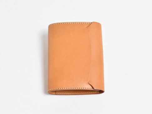 淺棕色皮革製成的A6記事本書套，簡約設計，邊緣有縫線裝飾，整體呈長方形，有翻蓋設計。
