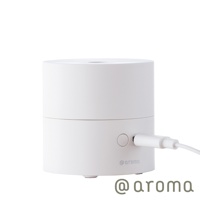 白色圓柱形隨身精油香氛機，頂部有出霧孔，側面有電源按鈕及USB充電孔，機身印有@aroma標誌，整體為光滑的塑膠或金屬材質。