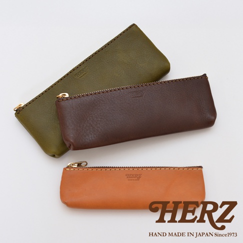 職人手作皮革經典收納筆袋，展現三款顏色：墨綠、咖啡色、棕褐色。筆袋均採用細緻皮革材質，搭配精緻縫線與金色拉鍊，展現質感。