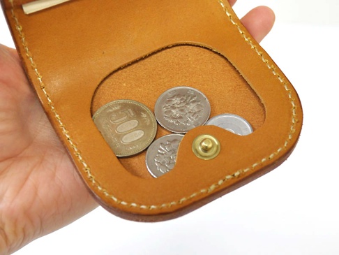 職人手作皮革馬蹄造型零錢包，採天然棕色皮革製成，縫線清晰，內部裝有數枚日圓硬幣，含一枚五百日圓硬幣，並配有金色按扣。