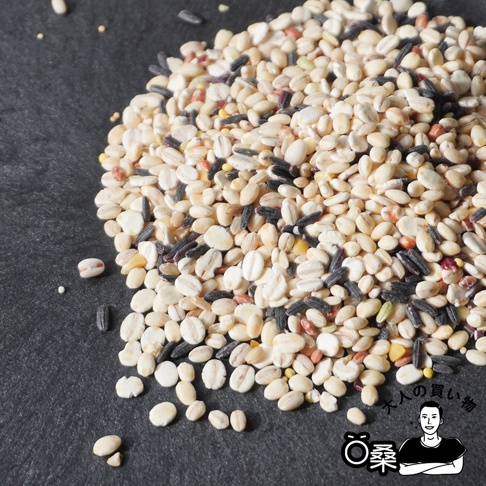 一堆日本國產十六穀米，混合了多種穀物，包括白米、黑米、大麥等，呈現米白色、深黑色、淺黃色等豐富色彩。