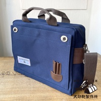 藍色純綿帆布製成的三用橫式側背包，配有咖啡色皮革裝飾和提把，側邊有可拆卸背帶。