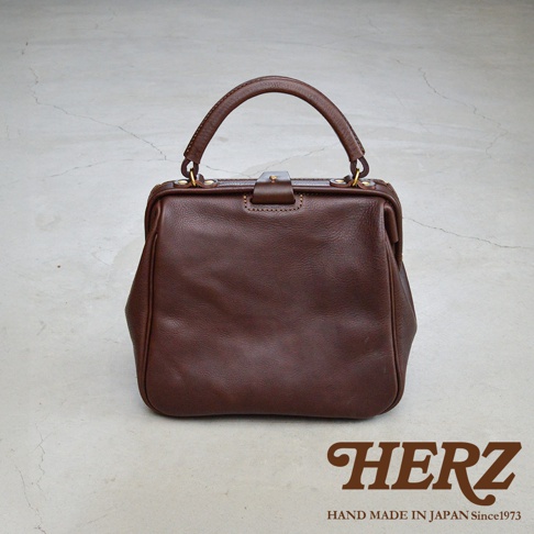 深棕色皮革手提包，方形口金設計，配有皮革提把和金屬釦環，整體風格經典。