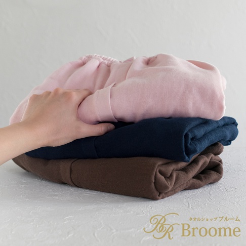手部觸碰堆疊的浴裙，上方為粉紅色，中間為海軍藍，下方為咖啡色，皆為棉紗混紡材質。