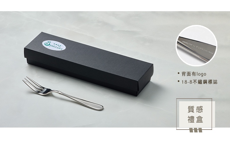 一隻不鏽鋼點心叉放在黑色禮盒旁，叉子採用簡潔的設計，呈現金屬光澤。