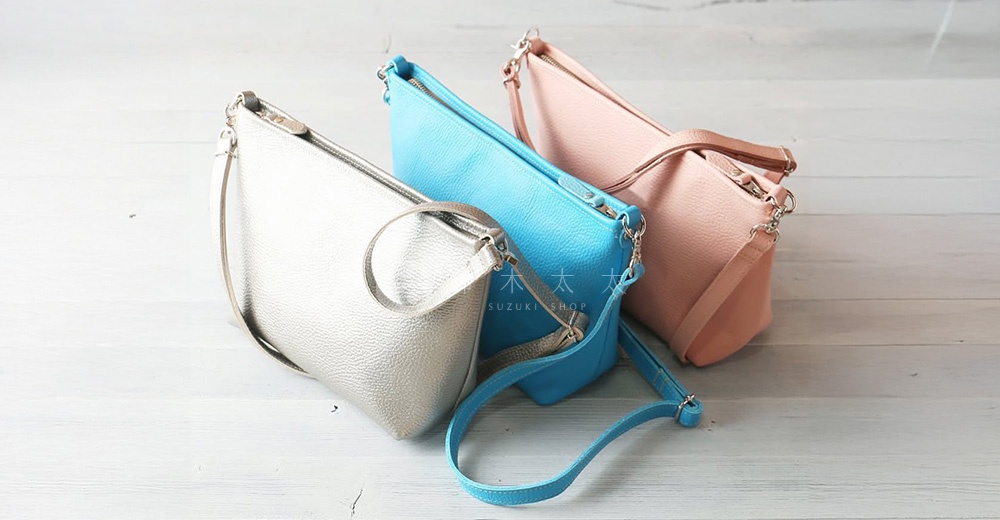 三款京都職人手作隨身側背包，分別為銀色、藍色與粉紅色，皆為皮革材質，配有金屬拉鍊與可調式背帶。