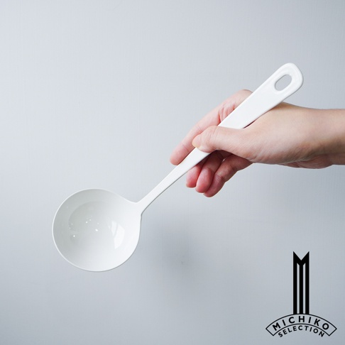手持白色湯勺，勺柄上有掛孔，背景為淺灰色。