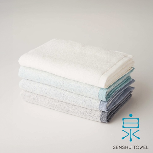 YUKINONE 雪之音柔織有機棉迷你浴巾，疊放著四條不同顏色的浴巾，由上至下分別為白色、淺藍色、淺灰色與深灰色。浴巾觸感柔軟，邊緣有細緻的縫線。