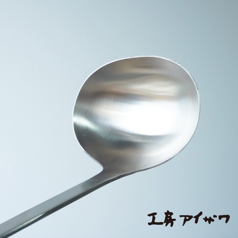 一個不鏽鋼萬用湯勺，勺頭呈圓形，勺柄細長，整體為銀色金屬質感，勺身有細微的反光。