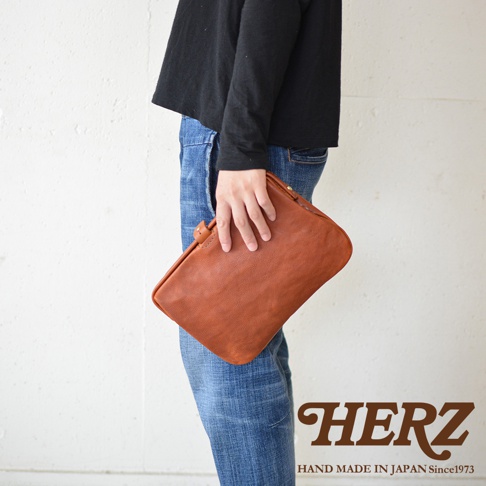 職人手作皮革Organ手拿包，呈現自然的棕褐色，皮革材質，款式簡約，適合日常攜帶。