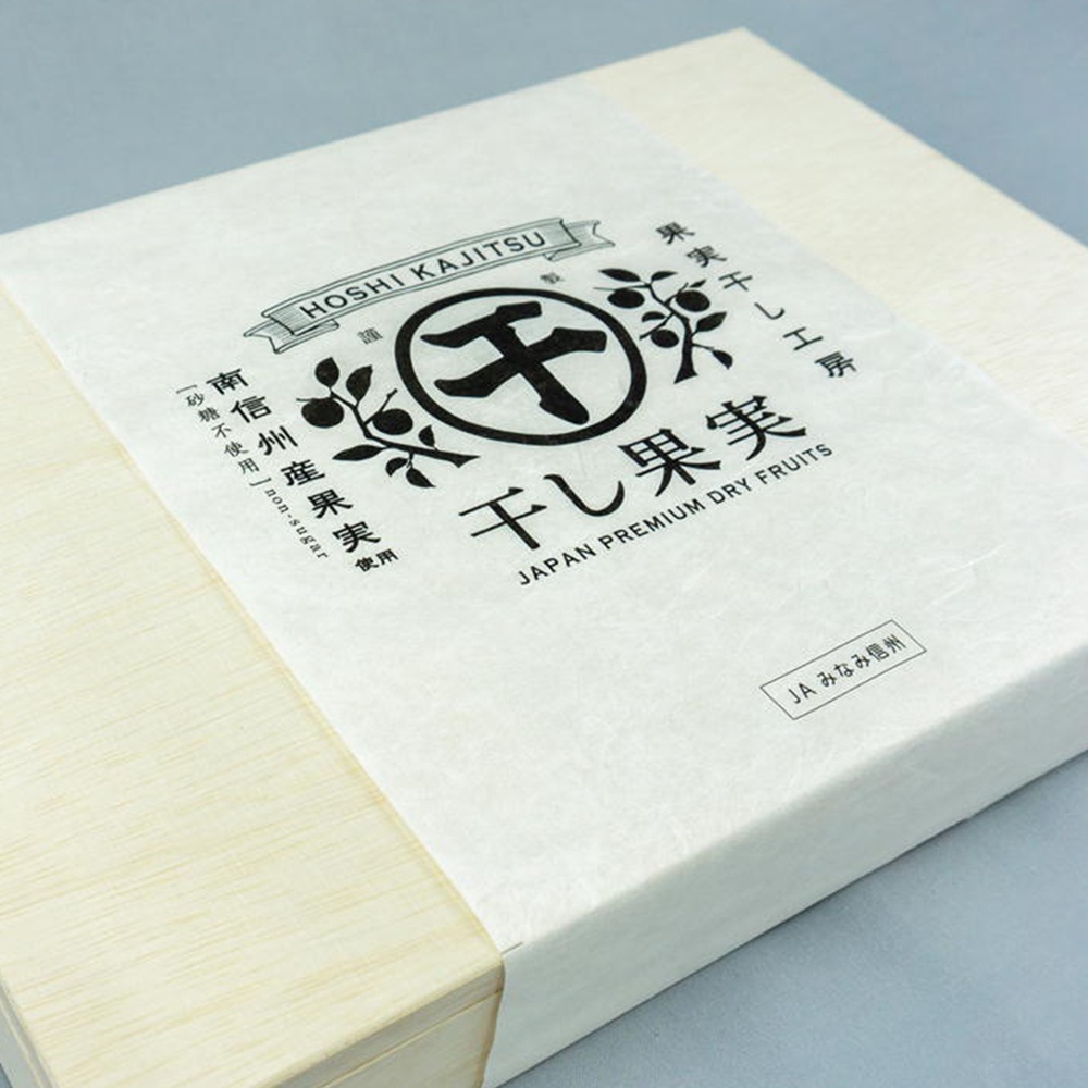 長野縣南信州果乾20入桐木禮盒，淺色木質禮盒，覆蓋著印有日文「干し果実」與英文「JAPAN PREMIUM DRY FRUITS」字樣的白色包裝紙，中央有「千」字圖案及果實枝葉裝飾，左側有「無砂糖使用」標示。
