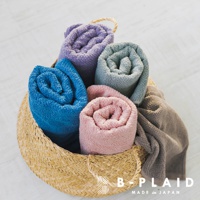 編織籃中擺放著五條捲起的毛巾，顏色分別為藍色、粉色、紫色、淺綠色和灰色。毛巾材質柔軟，帶有細緻的紋理。