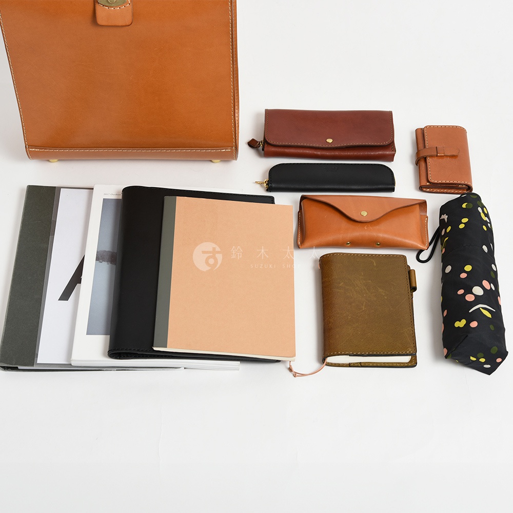 皮革商務後背包、長夾、短夾、筆記本、手機包、筆袋及花紋雨傘，以不同尺寸和顏色陳列。