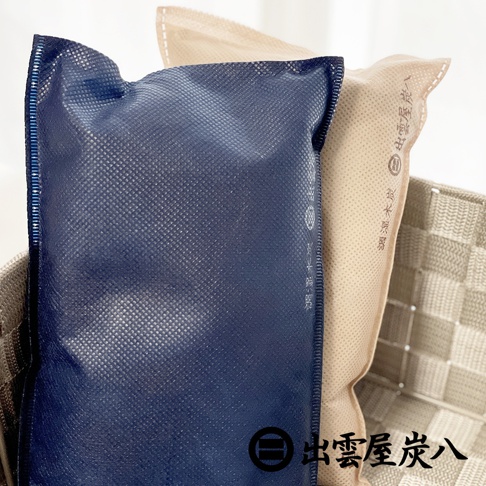 深藍色與米色調的調濕木炭包，表面有網狀紋理，邊緣車縫線明顯，其中米色包上印有中文文字。