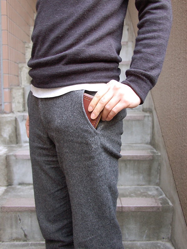 職人手作皮革全包式拉鍊短夾 (WS-40)，棕色皮革材質，拉鍊設計，置於灰色褲子口袋中。