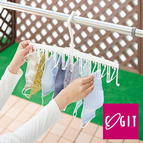 白色多孔晾衣架上掛有數件印花和素色布料，由雙手調整。