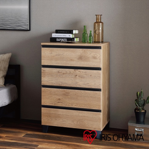 淺木紋五層抽屜式收納櫃，搭配黑色櫃腳和黑色抽屜條。櫃面有木紋質感，頂部擺放有書籍、綠色玻璃瓶和琥珀色玻璃瓶。