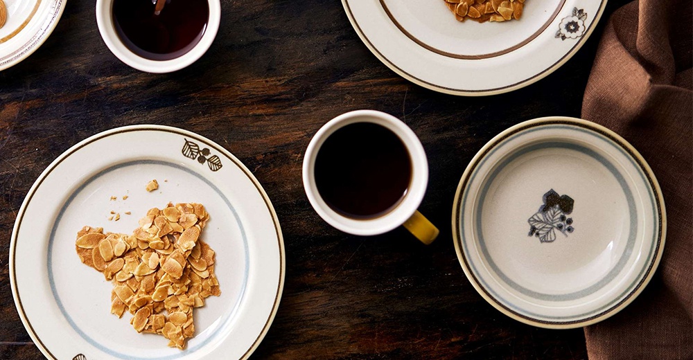 美濃燒葉紋復古溫潤小碗，白色陶瓷碗身，邊緣飾有褐色及藍色條紋，碗內印有深藍色葉子圖案。