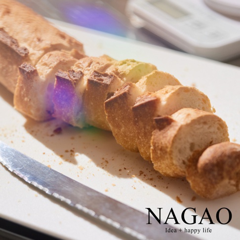 白色砧板上擺放著切片的法式長棍麵包，旁邊是鋸齒狀的銀色刀刃。