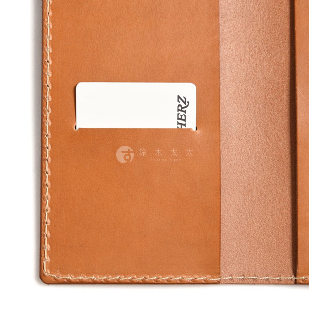職人手作皮革輕便記事本書套，採用棕色皮革，內有卡槽，其中一個卡槽露出部分白色卡片，上面印有「HERZ」字樣。