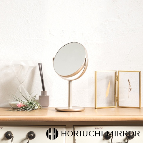 香檳金圓形桌上化妝鏡，鏡面可調整角度，鏡框與支架皆為金屬材質，呈現質感。