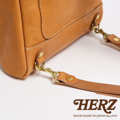 職人手作皮革大開口圓角後背包 R-18，展示包款側邊細節，採用天然棕色皮革，配有黃銅色金屬扣環及可拆卸背帶。