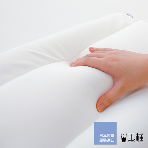 一隻手按壓在白色柔軟的「王様の小王子夢枕」上，枕頭呈現出良好的支撐性和回彈性。