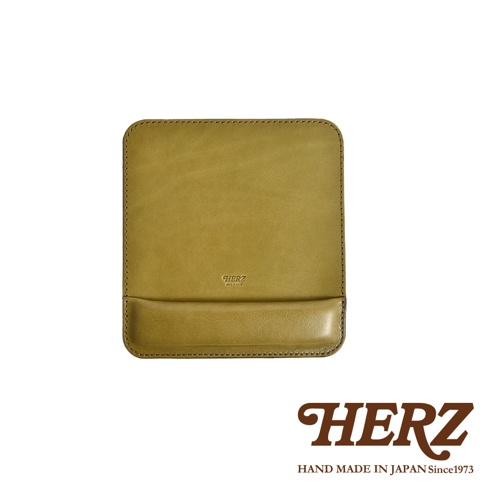 職人手作皮革滑鼠墊 KZ-2，採用質樸的橄欖綠色皮革製成，表面壓印有「HERZ」品牌標誌。滑鼠墊帶有腕托設計，邊緣以車縫線裝飾，整體呈現簡約風格。